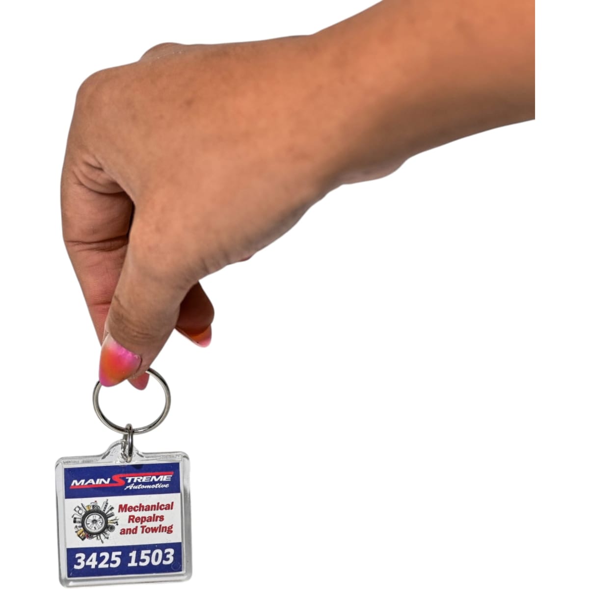 A hand holding a square acrylic keychain featuring a logo and text, predominantly red, blue, and silver.