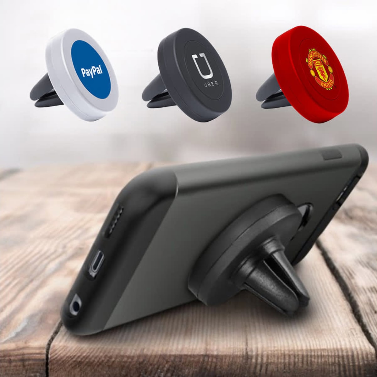 A phone holder with three varying coloured magnetic mounts: white, black, and red, displayed on a wooden surface.