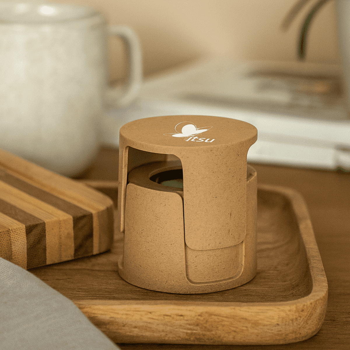 A wireless speaker made from plant fibre, featuring a natural brown colour and a logo on top, placed on a tray.