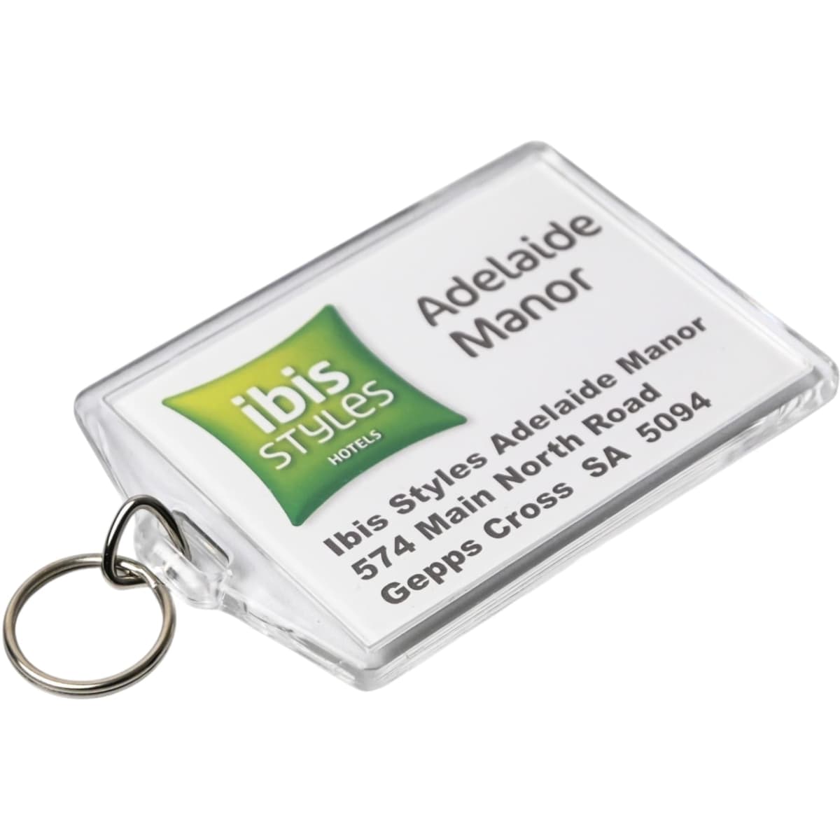 A clear hotel keychain featuring a logo and details for Ibis Styles Adelaide Manor, attached to a metal ring.