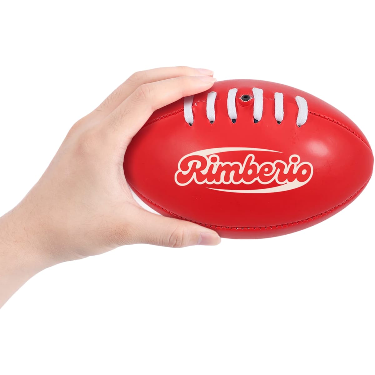 A red mini Australian Rules ball being held in a hand, featuring a logo on its surface.
