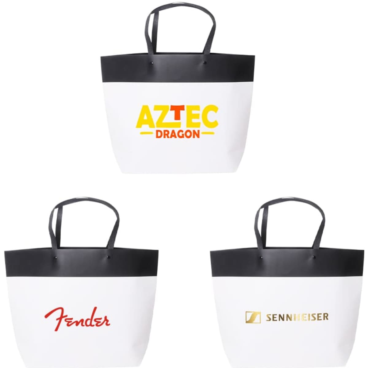 Three medium black and white boutique paper bags featuring black handles and various logos on the front.