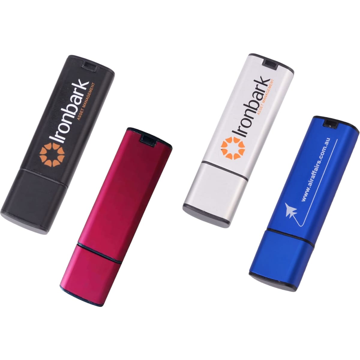 A set of four flash drives in black, pink, silver, and blue, each with a logo or branding.