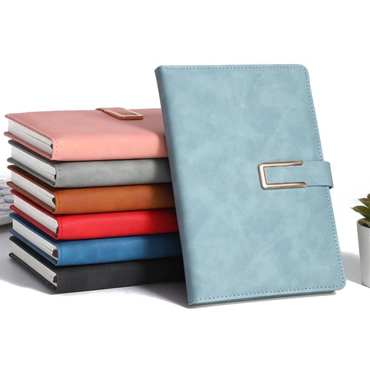 A collection of magnetic notebooks in various colours, including light blue, pink, orange, red, navy, and black, with a clasp.