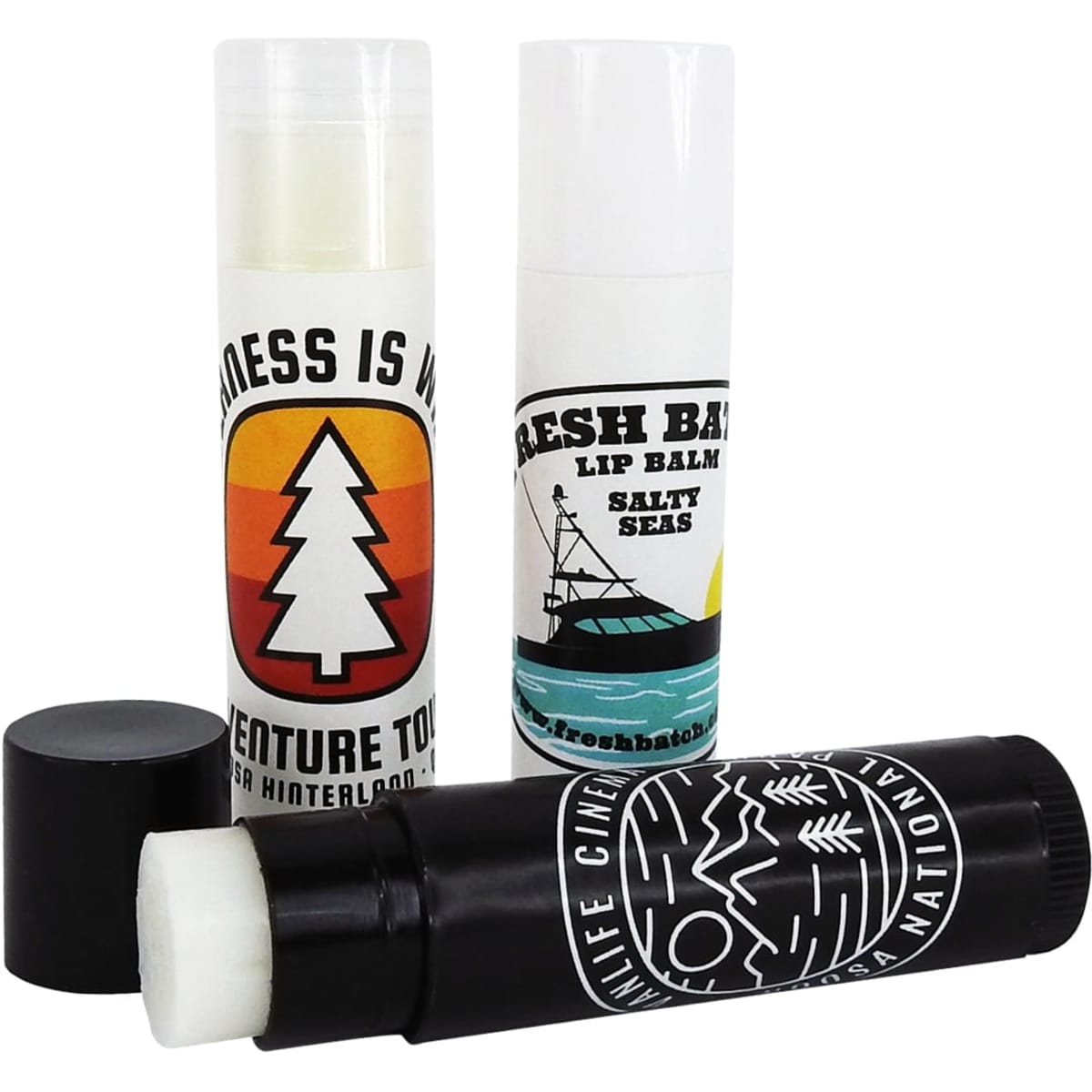 Three lip balm twist tubes in various designs and colours, including black, white, and green, with one featuring a logo.
