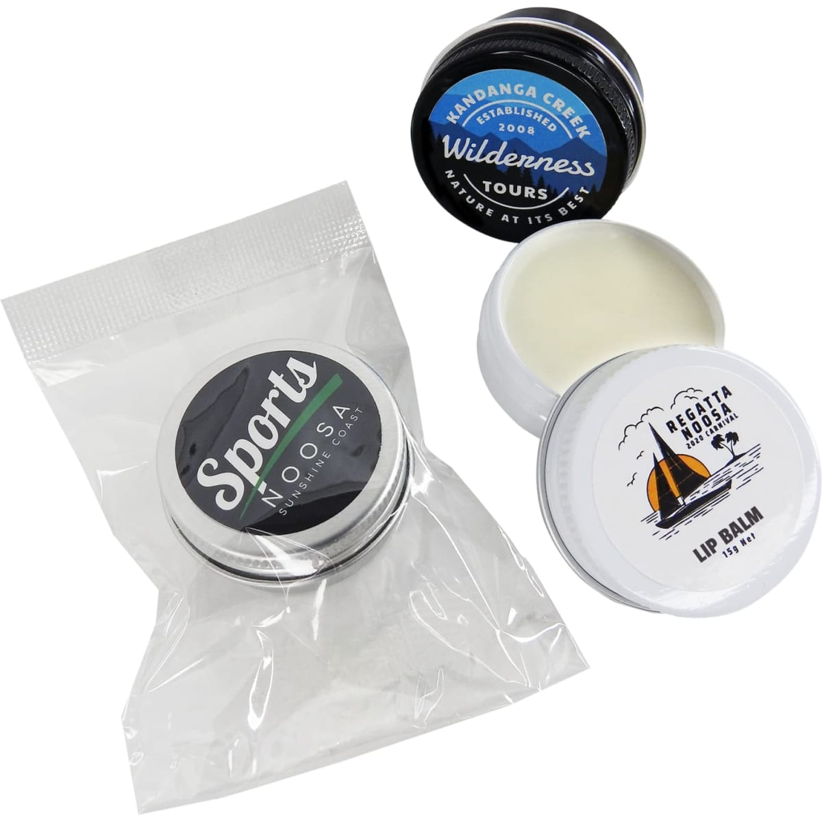 A collection of three twist-top tins, including a white lip balm and two additional tins, one with a black lid.