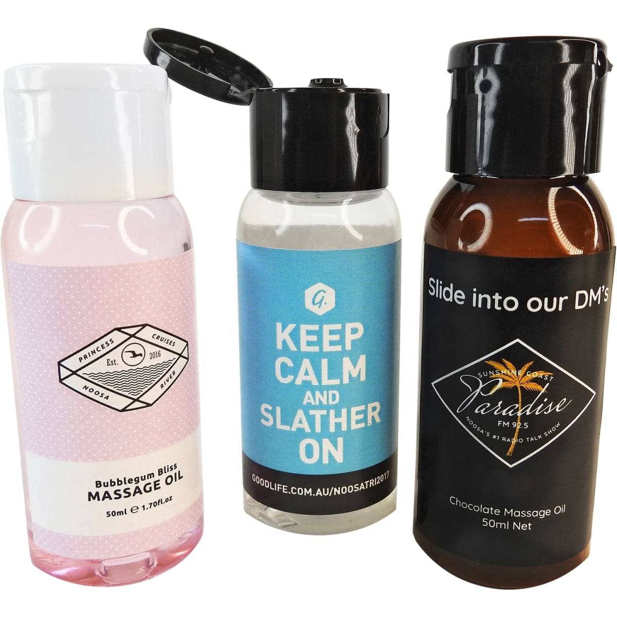 Three massage oil bottles in various colours: pink, blue, and brown, each with different shapes and a branded logo.