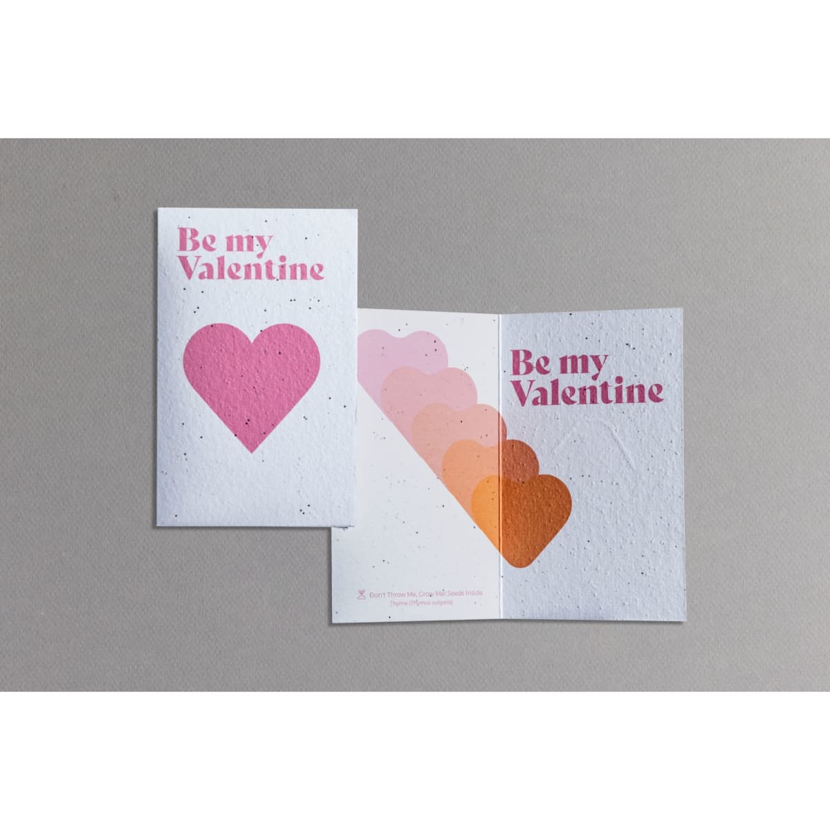 A medium seed paper greeting card in white and pink, featuring a heart design and 'Be my Valentine' text.