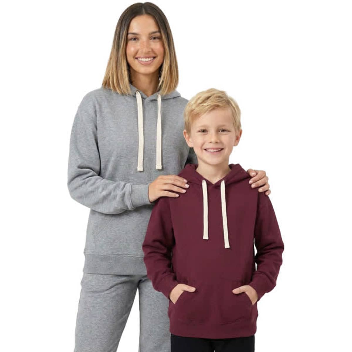 A grey women's heavy fleece hoodie and a maroon juniors hoodie, both with drawstrings and front pockets, are displayed by a model and a child.