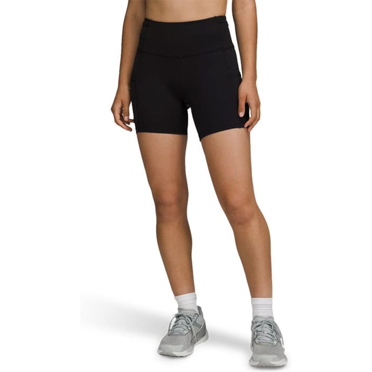 High-rise black legging shorts with a smooth waistband, featured on a model wearing grey sports shoes.