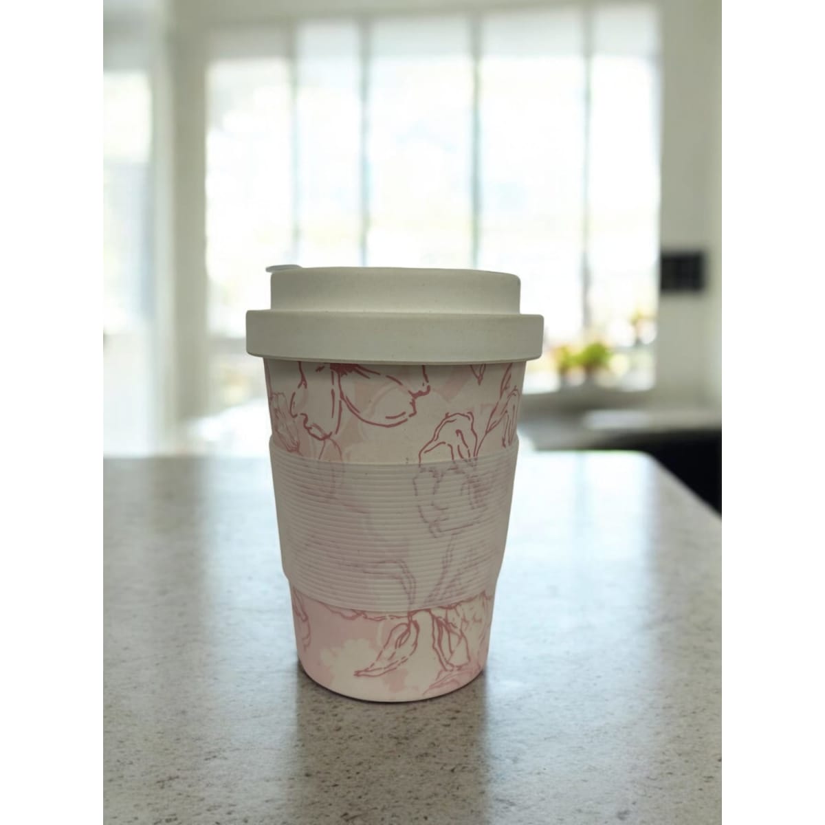 A reusable bamboo coffee cup with a hard lid, featuring a floral design in pink and white.