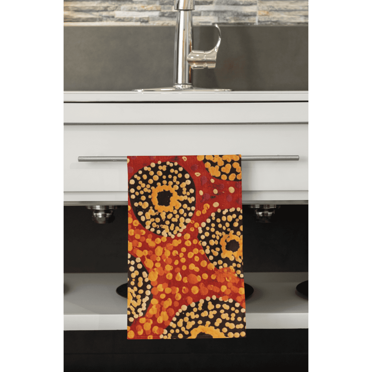 A multi-purpose towel in red, orange, yellow, and black patterns hanging from a kitchen towel rack.