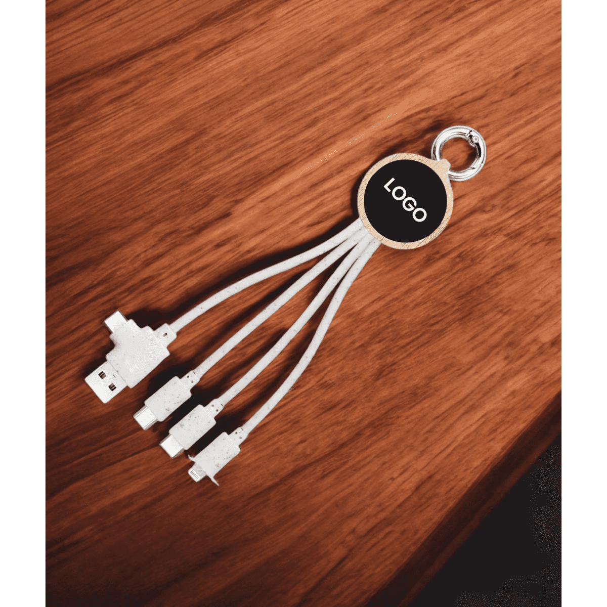 A multi charger cable with three white connectors, attached to a circular keyring, set on a wooden surface.