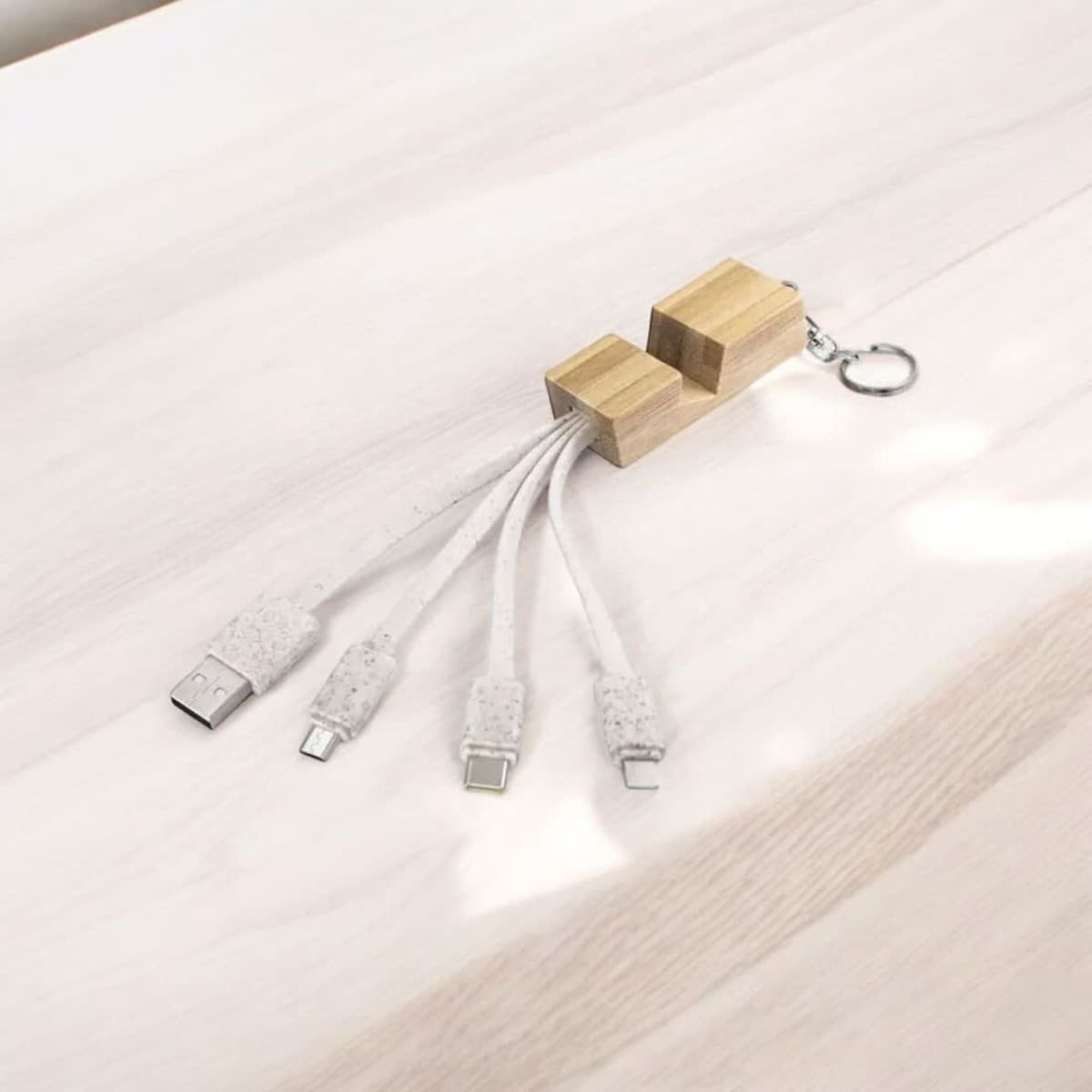 A sustainable multi-charger cable with white cables and a wooden connector, featuring a keychain attachment.