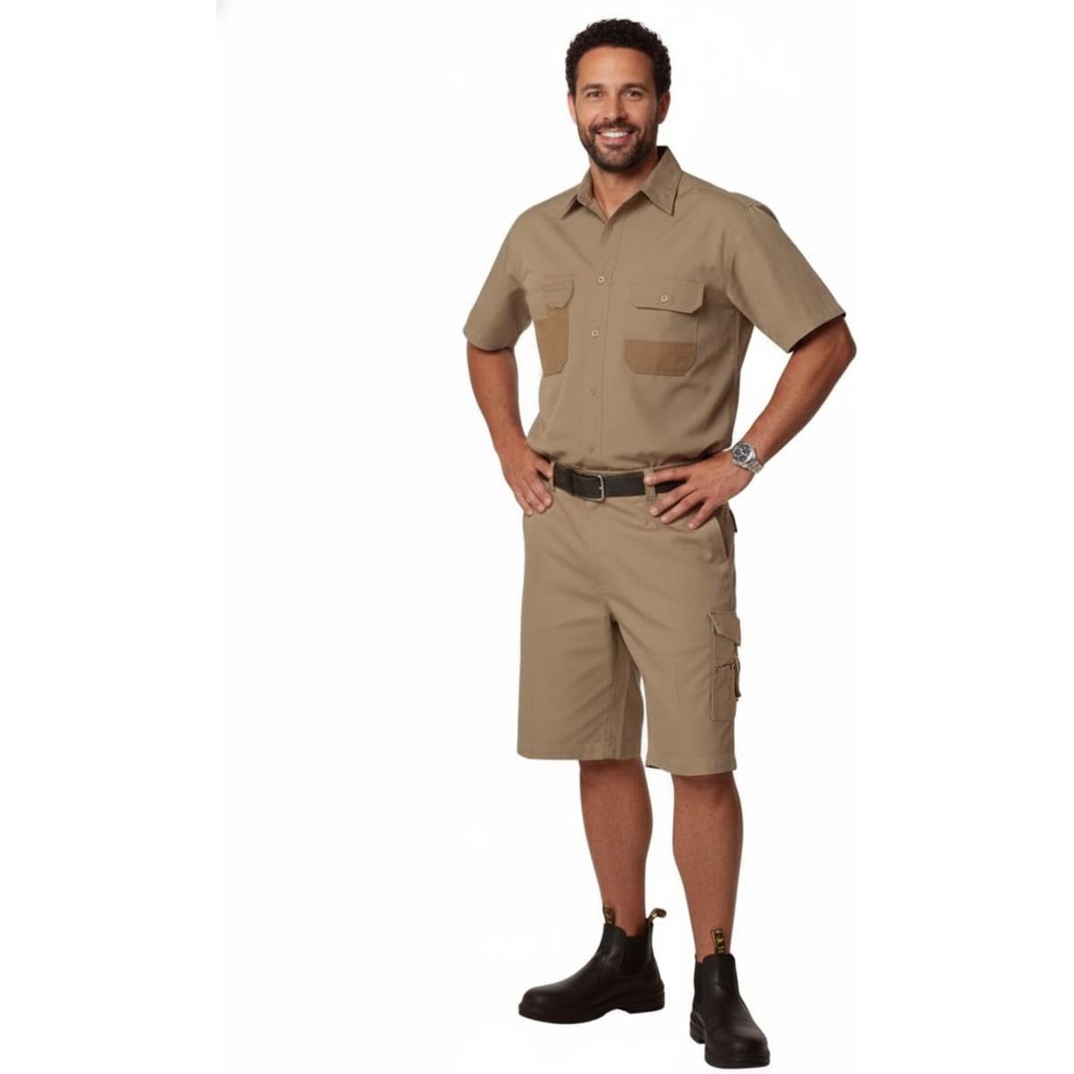 A man stands wearing khaki cargo shorts and a matching short-sleeve shirt. The outfit features pockets and a belt.