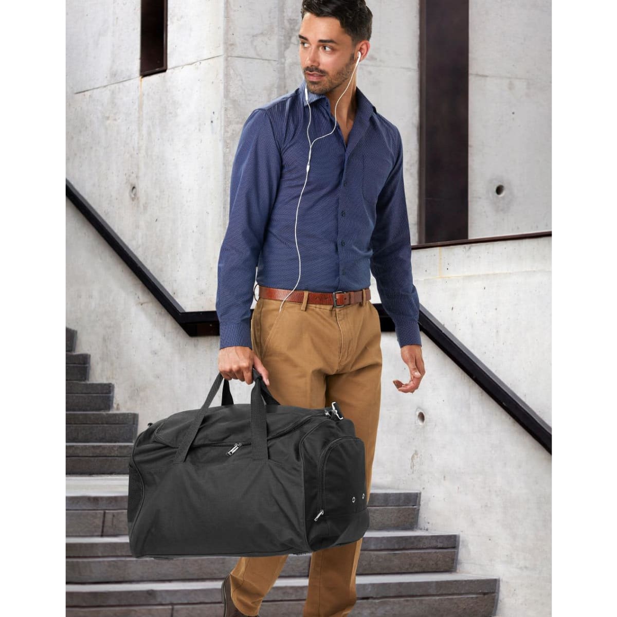 A red duffle bag with a zippered compartment and a pair of shoes resting against it. The bag has a logo.