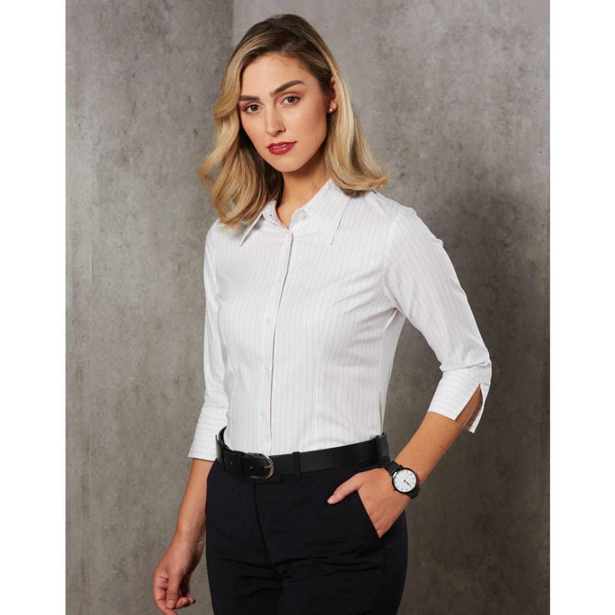 A white striped button-up shirt with long sleeves and roll-up detailing, paired with dark trousers and a watch.