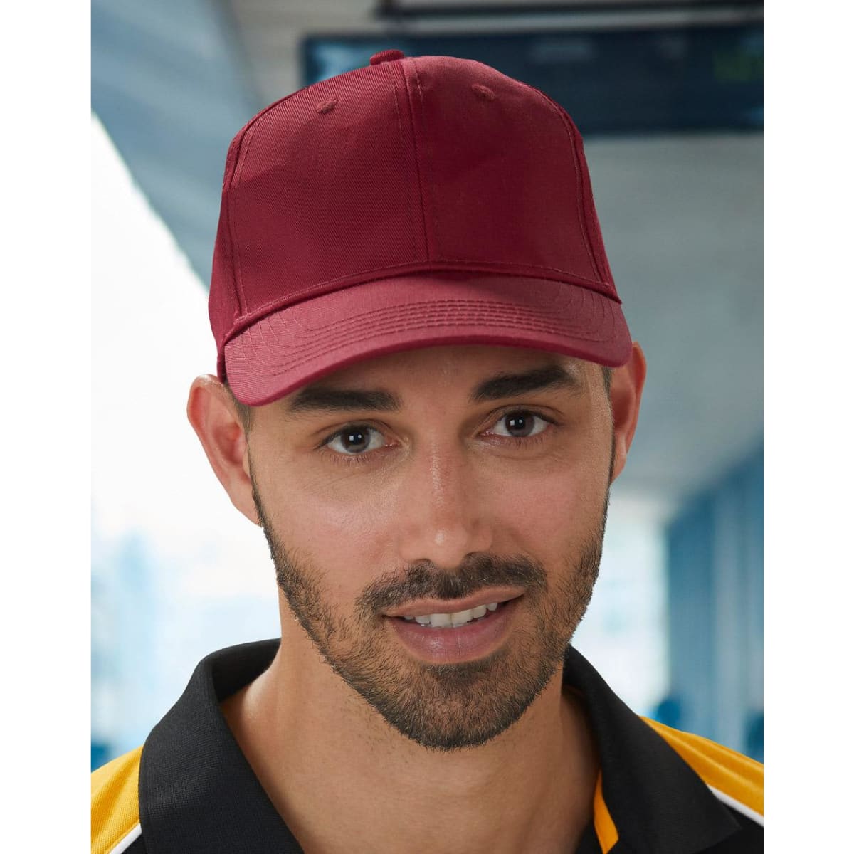 A red polycotton twill cap with a structured design and a front panel. It features a logo on the side.