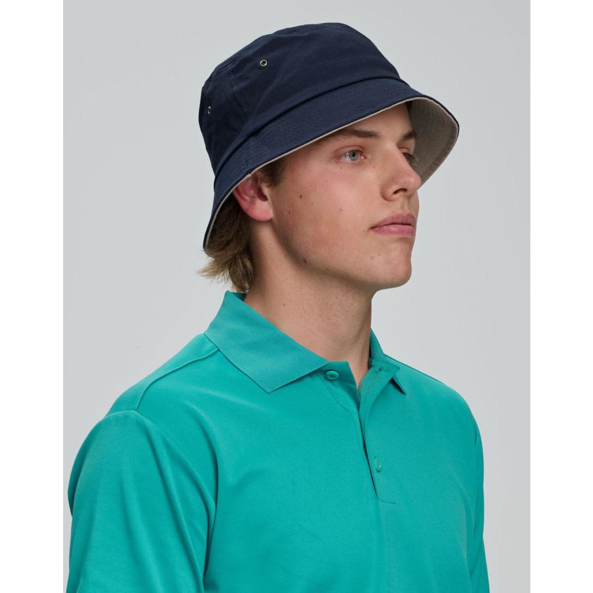 A beige bucket hat with a wide brim and ventilation holes, featuring a logo on the side.