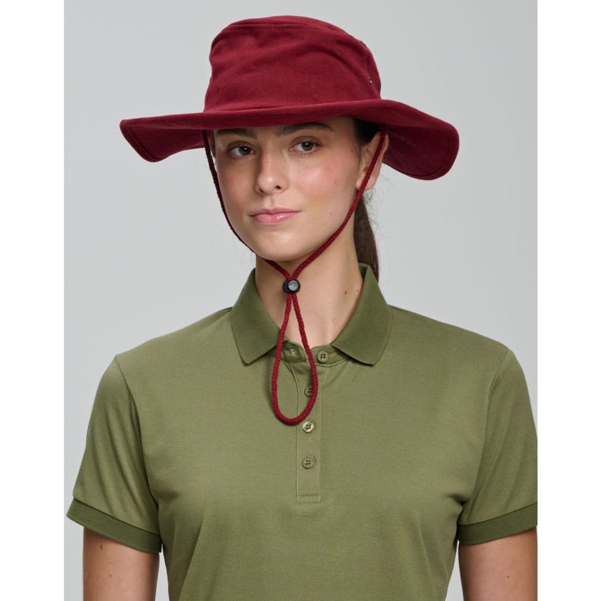 A beige bucket hat with a chin strap and a branded logo, featuring a wide brim for sun protection.