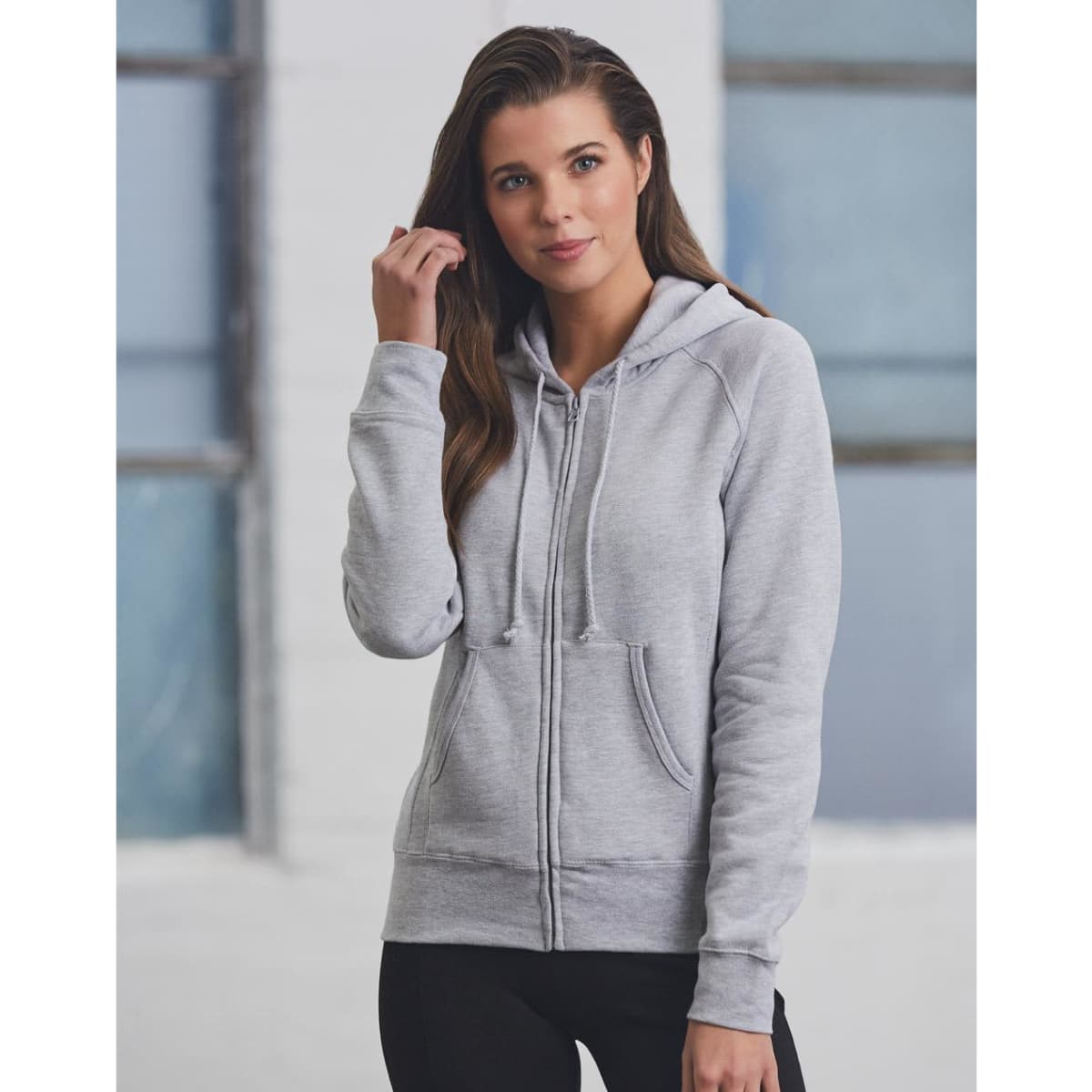A grey full-zip fleecy hoodie featuring a hood and drawstrings, worn by a model. It includes a logo.