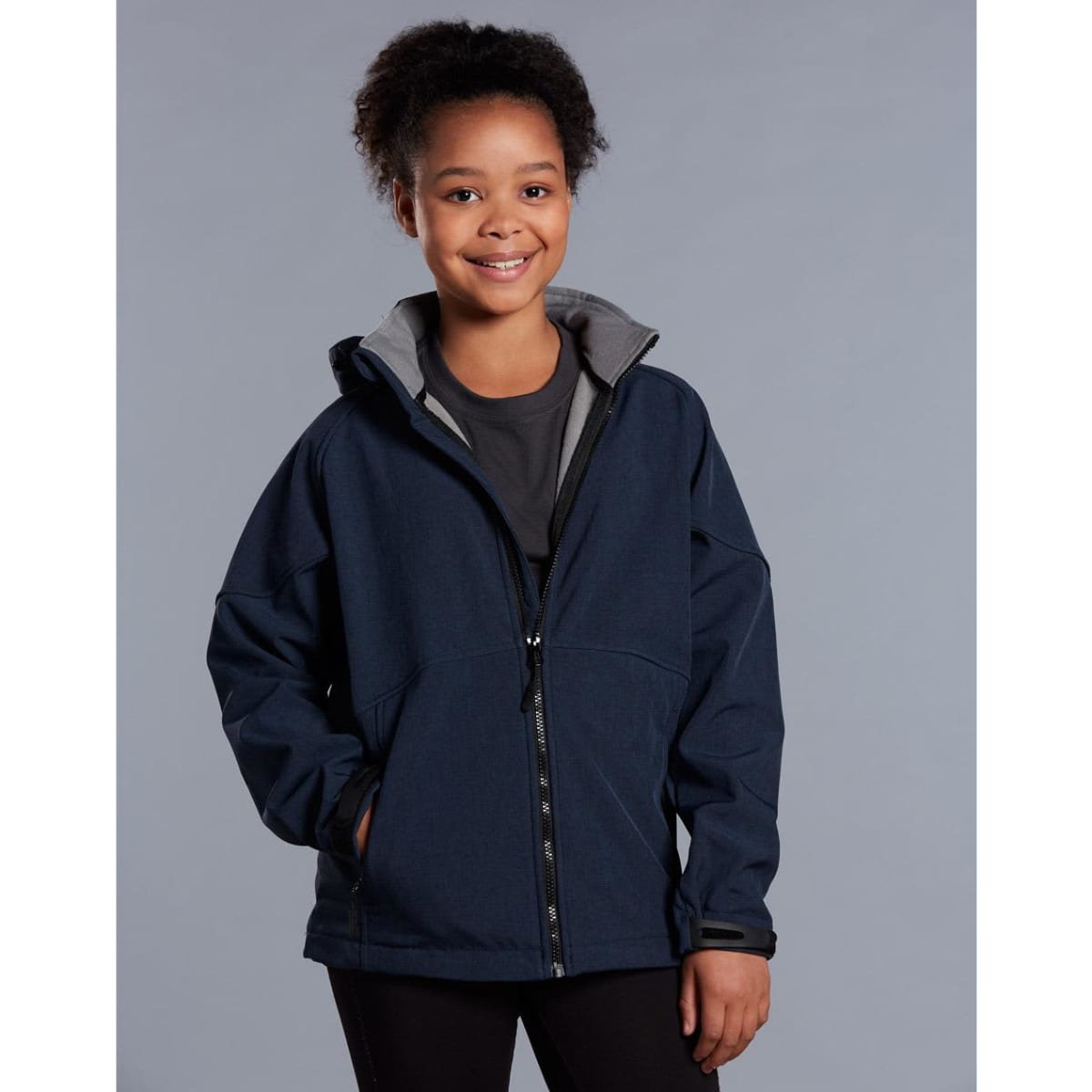 A navy softshell full zip hoodie with a grey interior, featuring a hood and zippered front, worn by a smiling child.