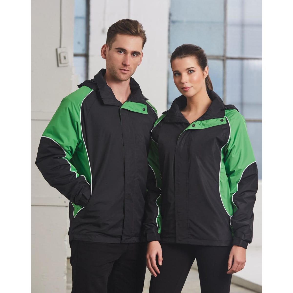 A unisex jacket in black with green accents, featuring a zip and a logo on the chest.
