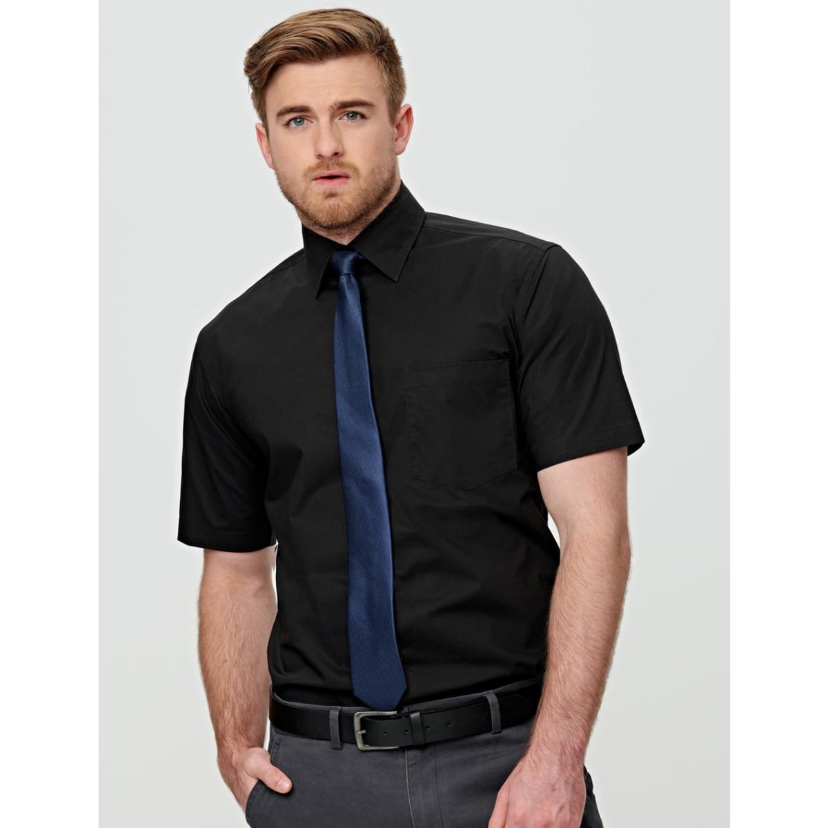 A black short-sleeve button-up shirt featuring a pocket and worn with a navy tie. The shirt has a logo.