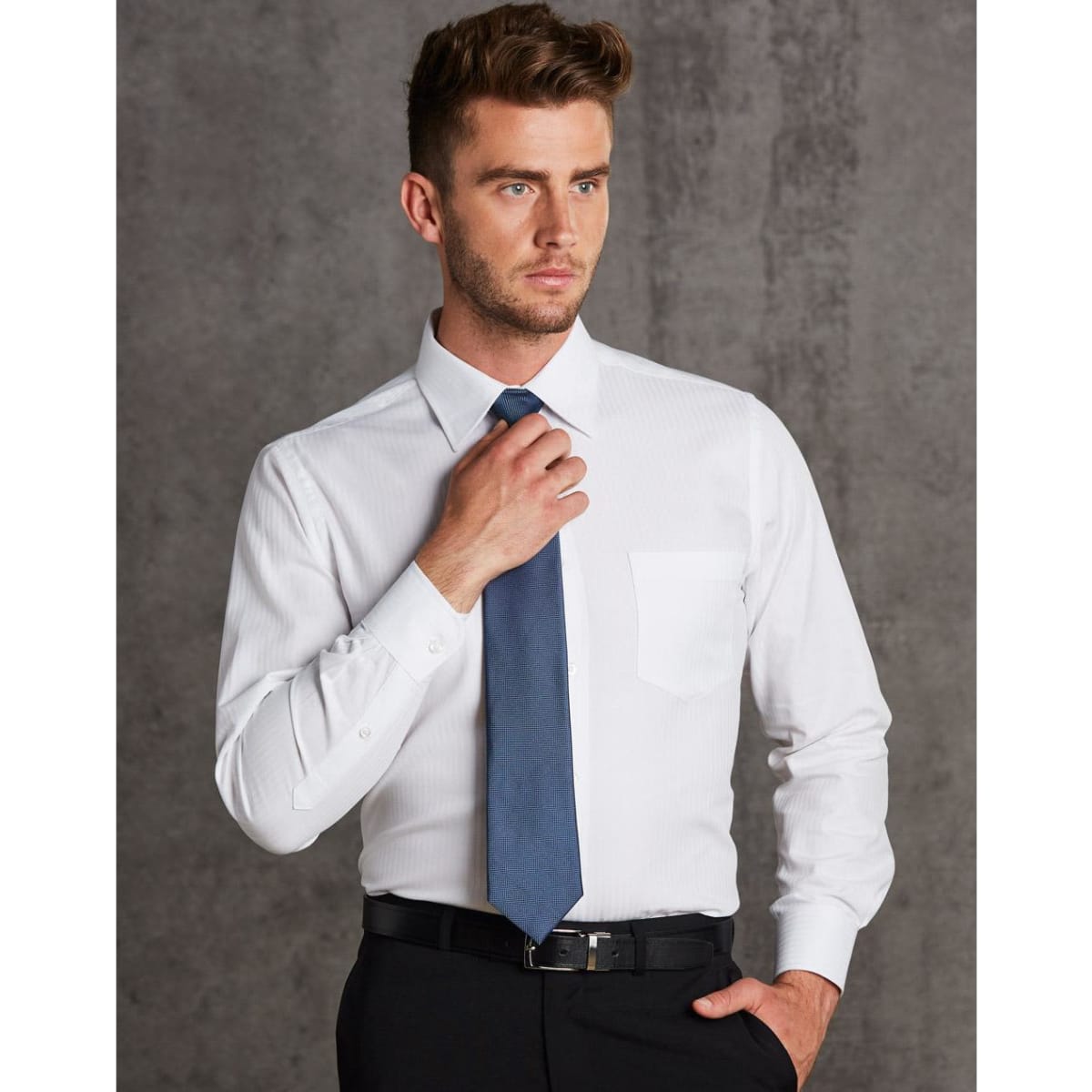 A white long sleeve button-up shirt with a pocket, worn with a blue tie and black trousers. The shirt features a herringbone pattern.