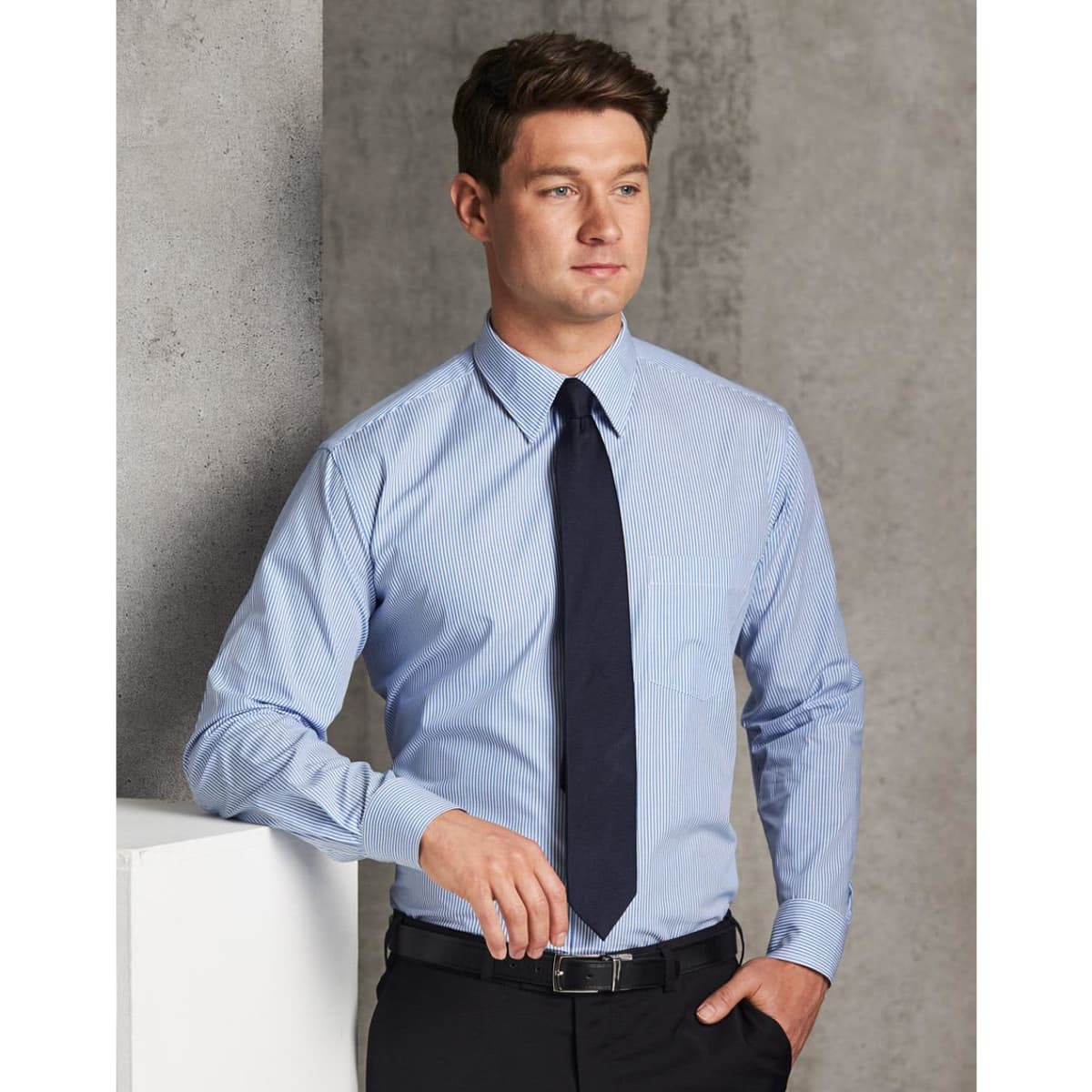 A men's long sleeve shirt in light blue with a stripe pattern and a dark tie, featuring a small logo.