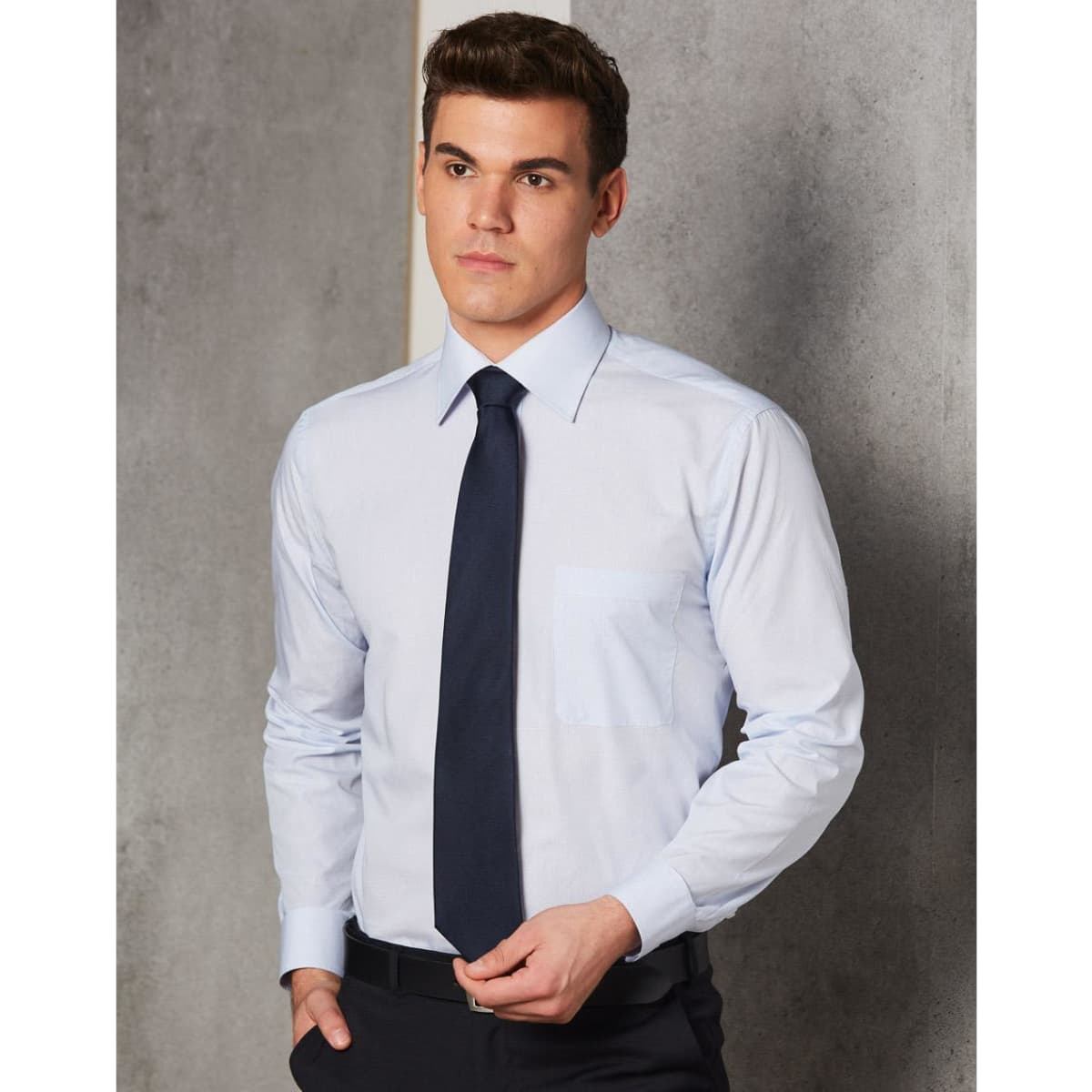 A light blue long sleeve button-up shirt featuring a single chest pocket and paired with a dark tie.