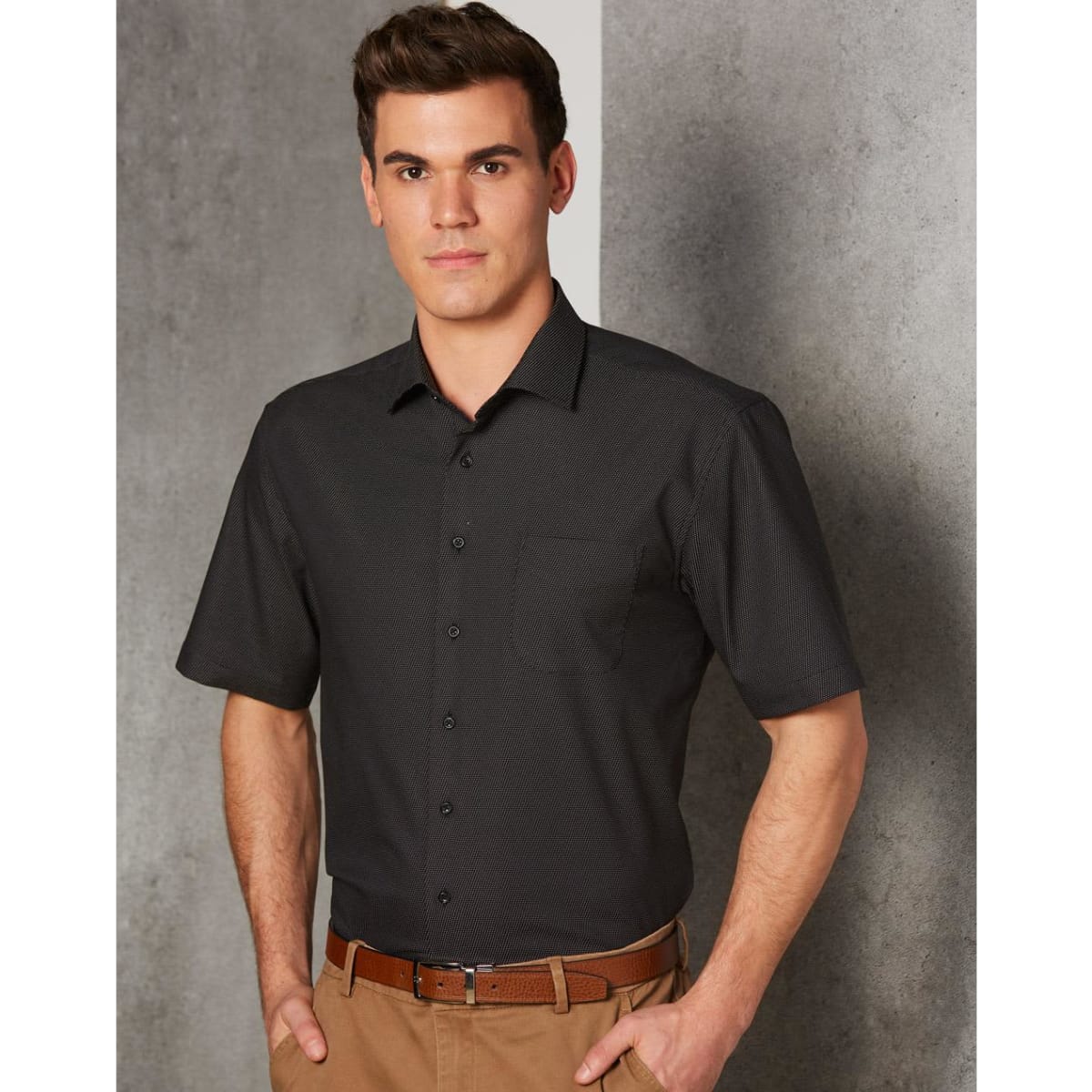 Men's short-sleeve button-up shirt in black with a pin dot pattern and a chest pocket. Features a logo.