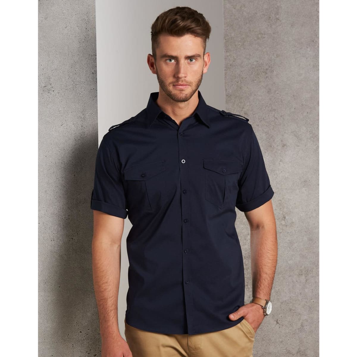 A men's short sleeve military shirt in navy with button-up front and two chest pockets, featuring a logo.
