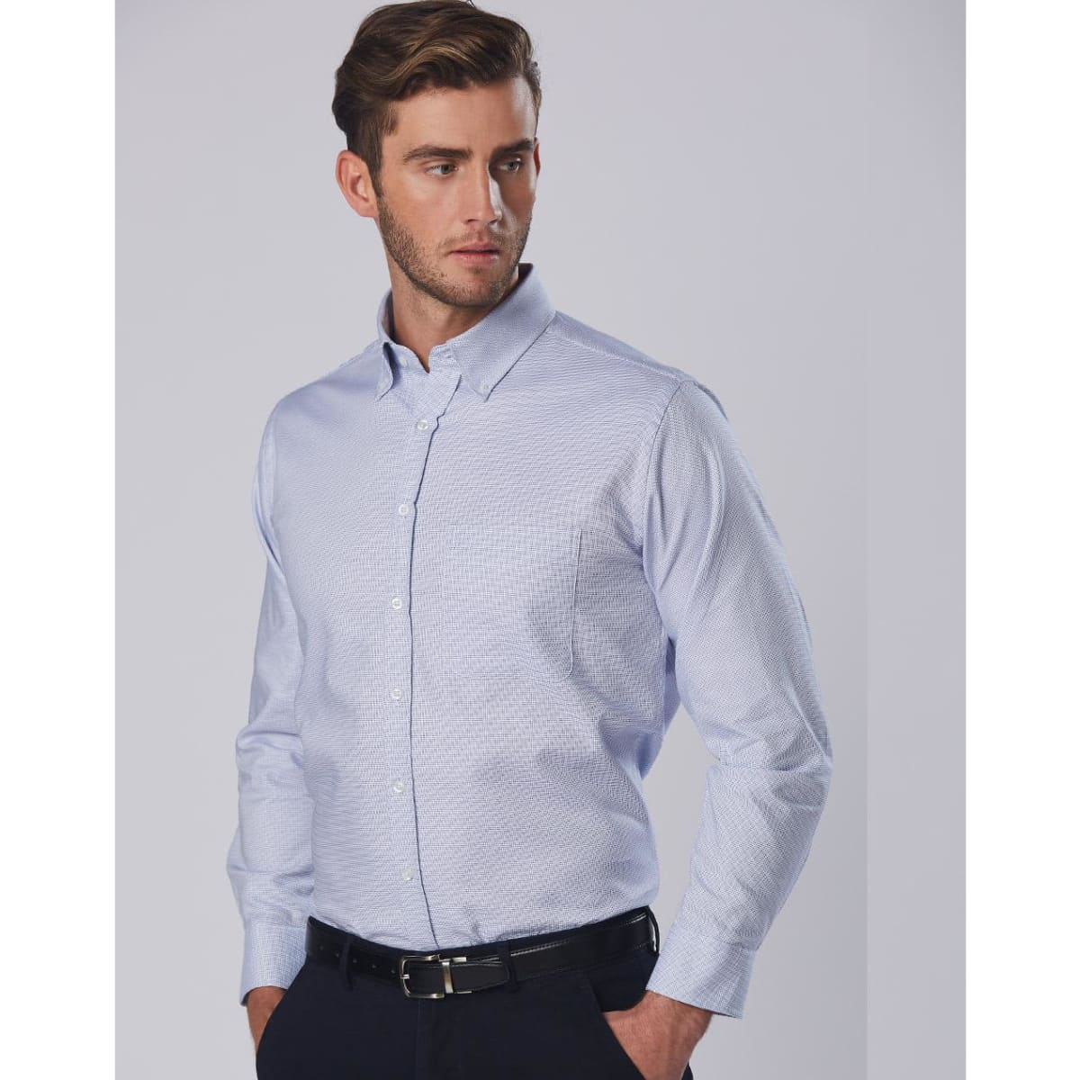 A long sleeve button-up shirt in light blue with a dot contrast pattern and a single chest pocket, featuring a logo.
