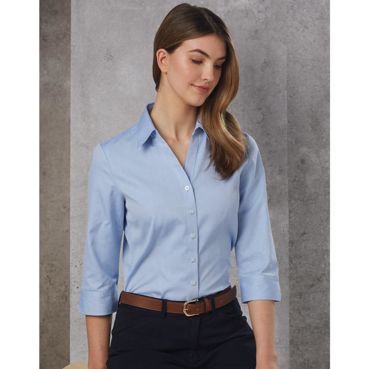 A light blue women's button-up shirt with 3/4 sleeves, featuring a collar and a sleek design, paired with a belt.