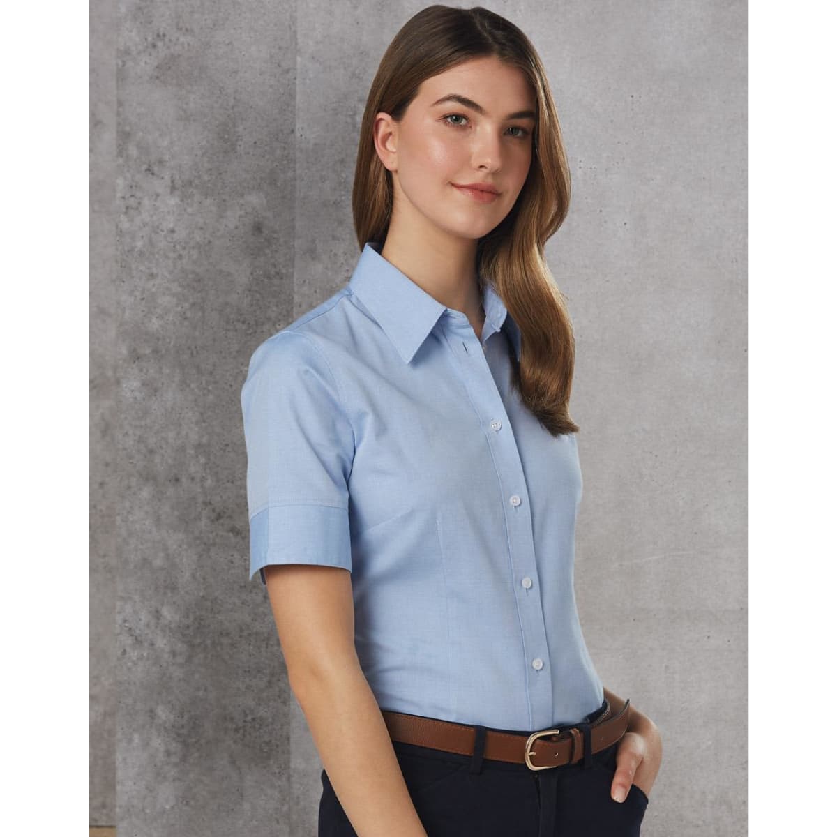 A blue women's short sleeve button-up shirt with a collar, featuring a logo on the chest and a belt.