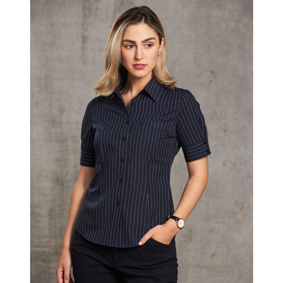 A women's short sleeve shirt in navy with a pin stripe pattern, featuring a button-up design and a logo.