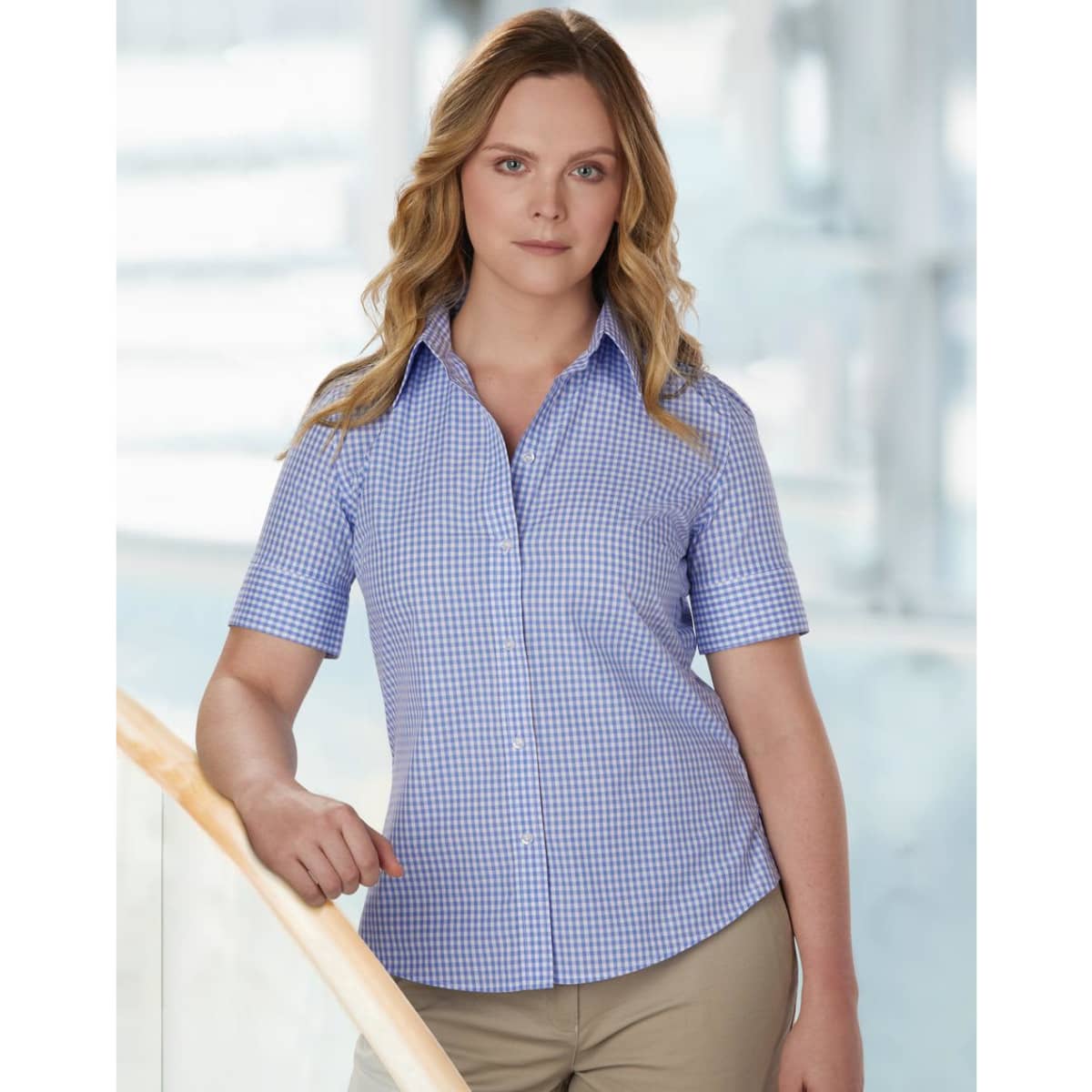 A fitted women's short-sleeve button-up shirt in red and white gingham check pattern, featuring a logo.