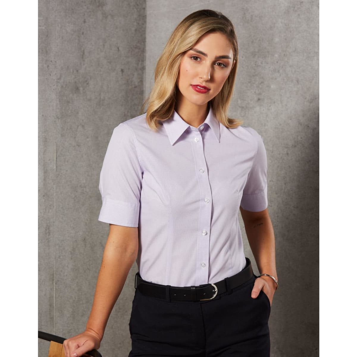 A women's short-sleeved button-up shirt in light purple with a collar and a logo.