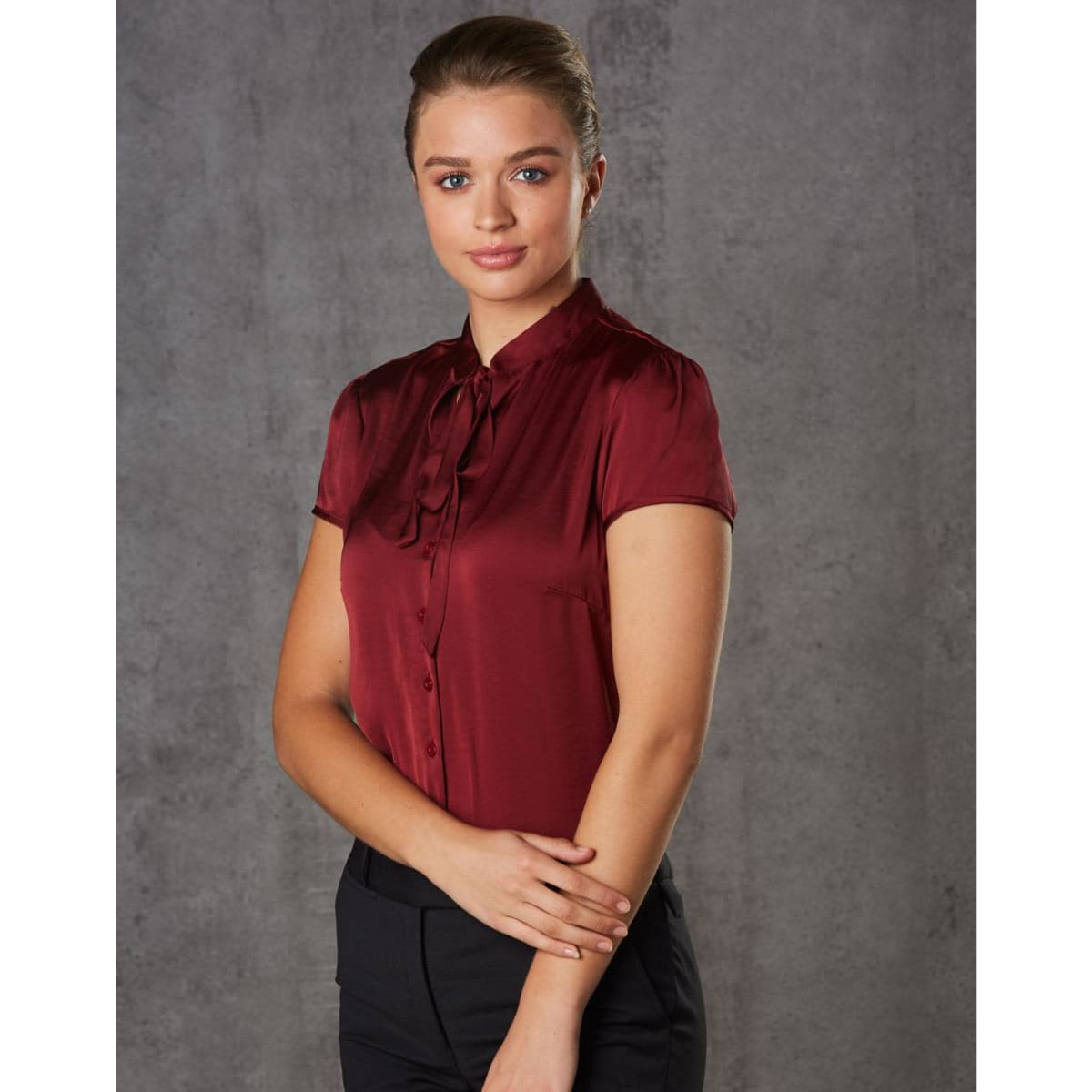 A maroon women's tie neck blouse with short sleeves, featuring a button-down front and a sleek, polished design.