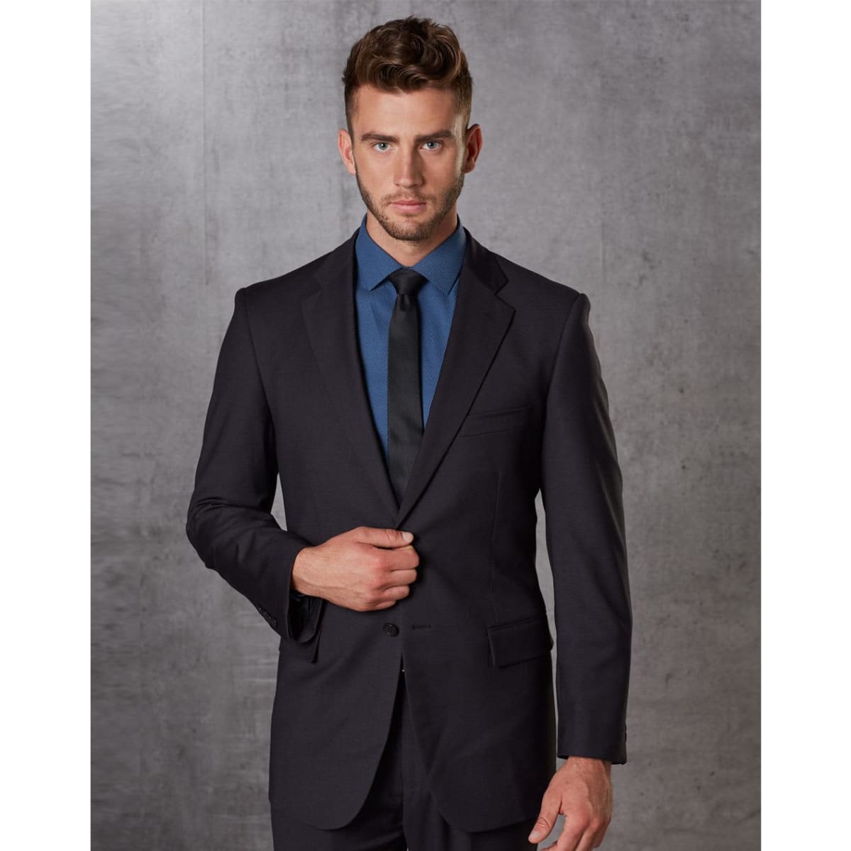 A men's dark grey poly/viscose stretch jacket, styled with a blue shirt and black tie, featuring a subtle logo.