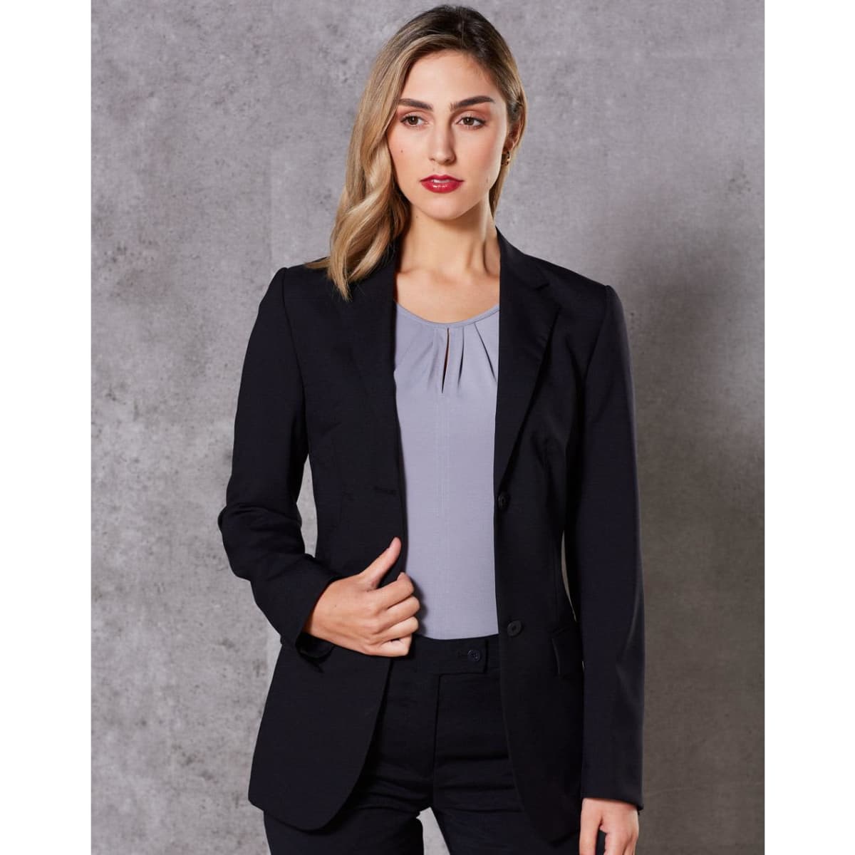 A women's mid-length jacket in black, featuring a tailored fit and a lapel collar, paired with a light grey top.