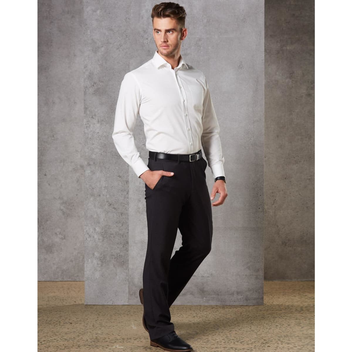 A man wearing black stretch wool blend pants paired with a white shirt and black shoes, standing in a modern setting.