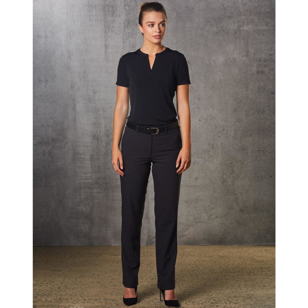 A woman wearing black Women's Flexi Waist Utility Pants, paired with a matching top, standing against a textured background.