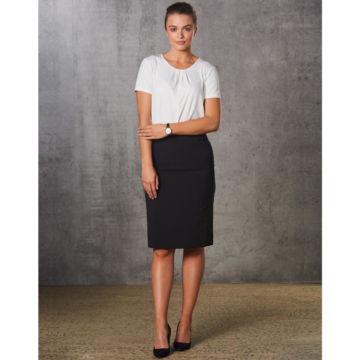 A model wears a black mid-length lined pencil skirt paired with a white top and high heels. The skirt features a subtle stripe pattern.