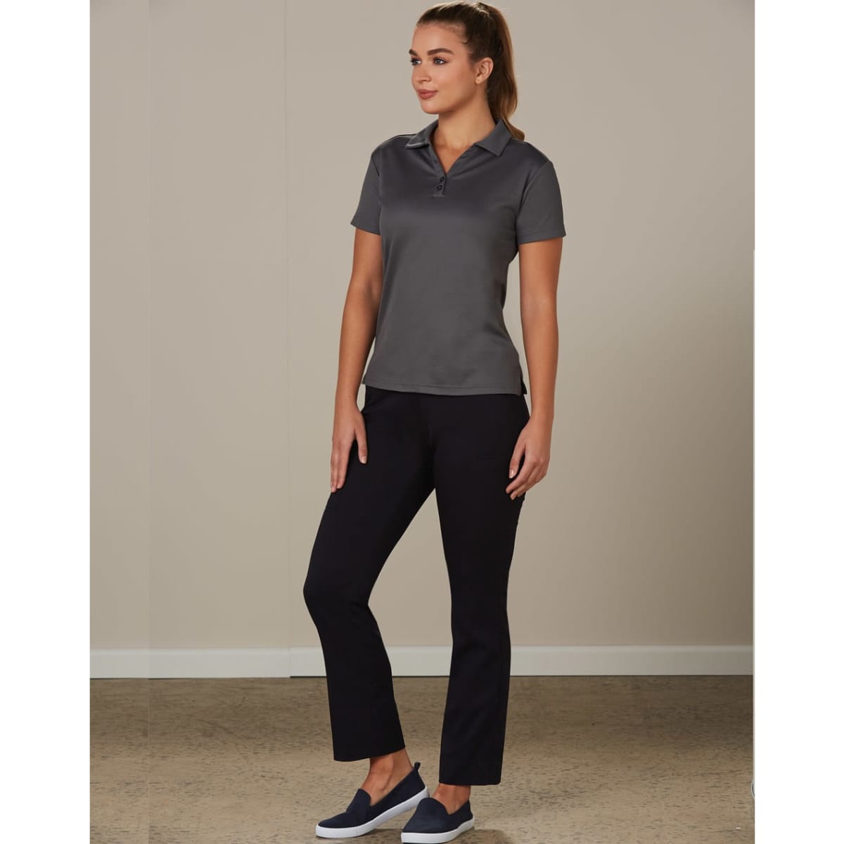 Ladies' utility cargo pants in black, paired with a grey polo shirt, model standing in a neutral setting.