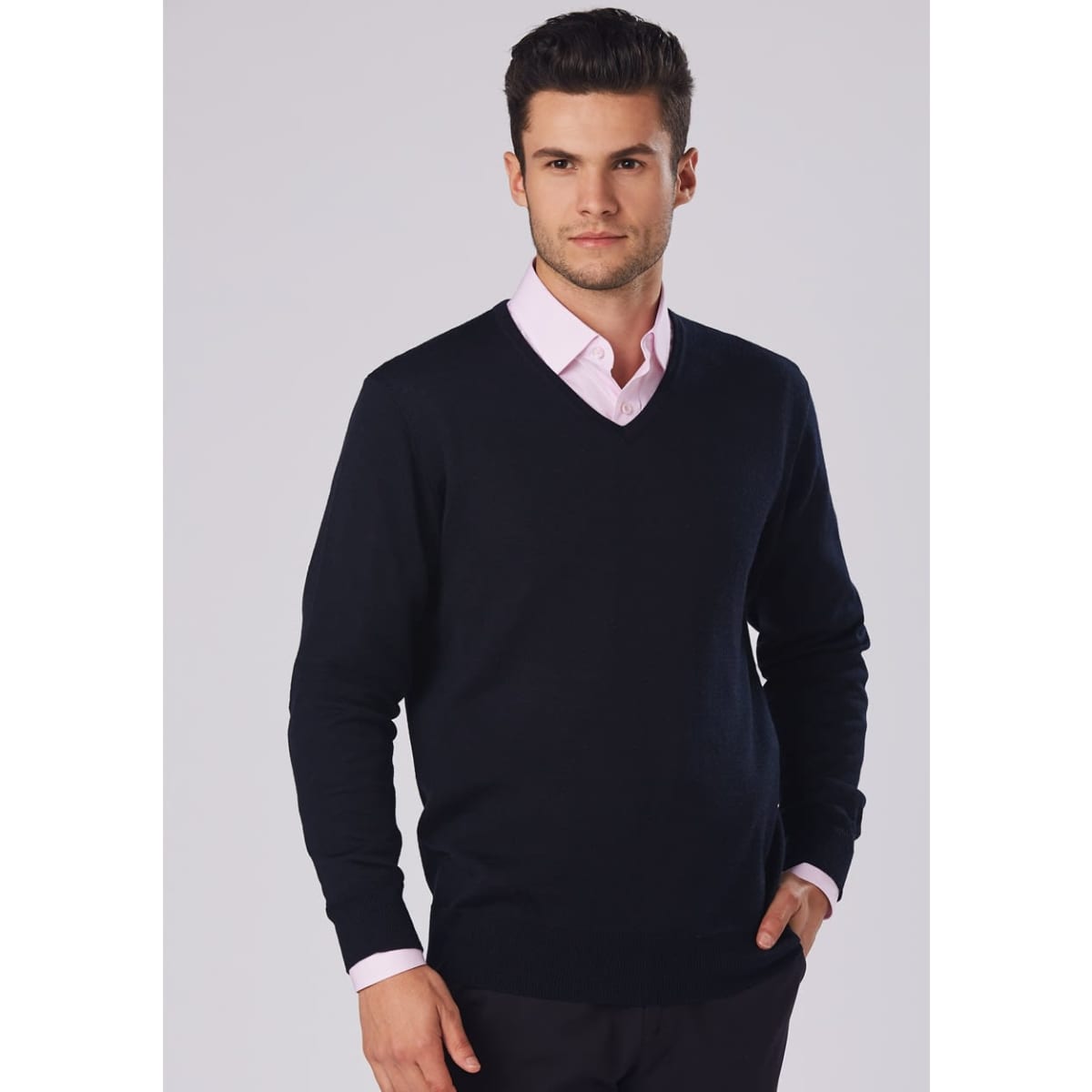 A men's 100% Merino wool V-neck long-sleeve sweater in navy, featuring a fitted design and worn over a light pink shirt.