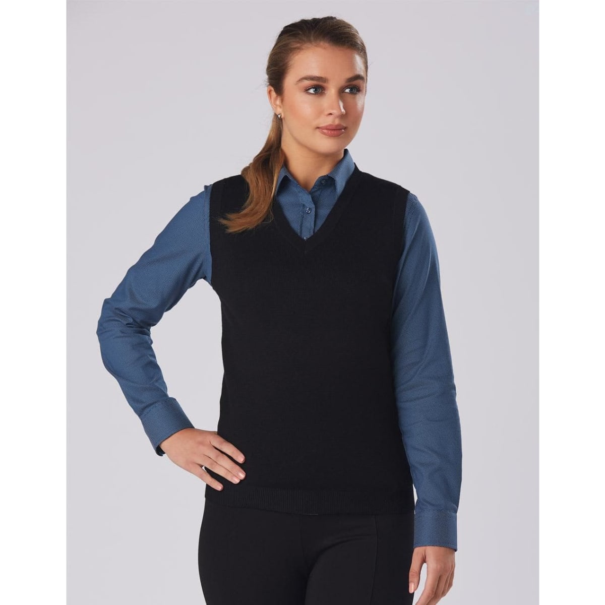 A black women's v-neck vest worn over a blue shirt, featuring a fitted design and casual style.