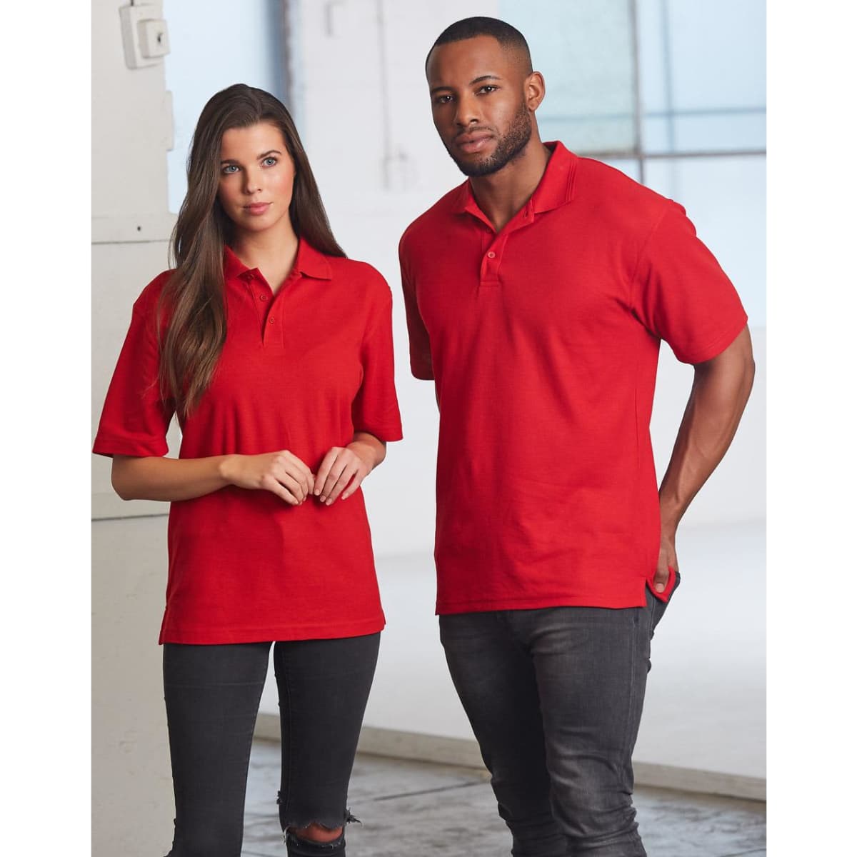 A unisex traditional polo shirt in bright red, displayed on a male and female model. Features a logo.