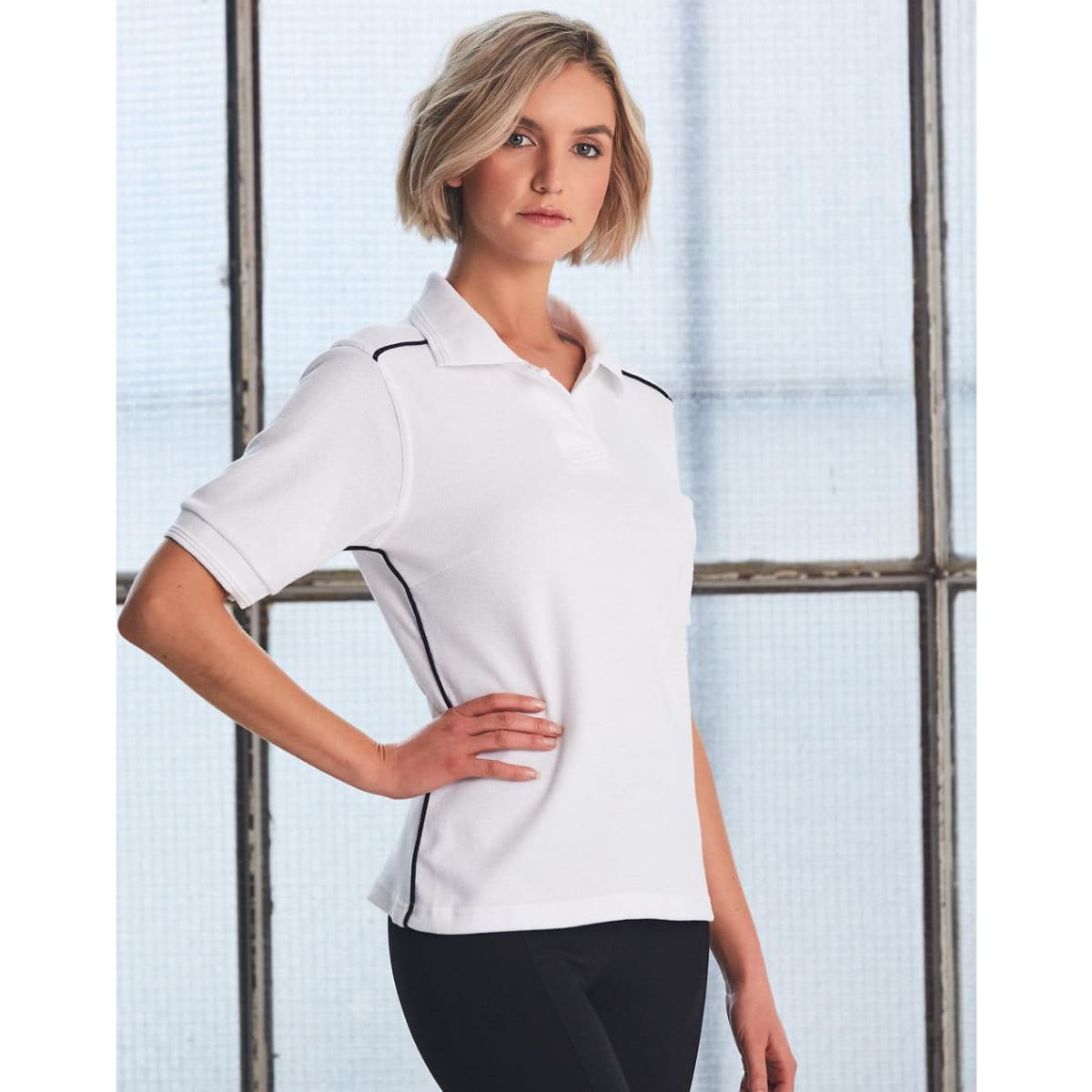 A white ladies' polo shirt with black side detailing and a branding logo.